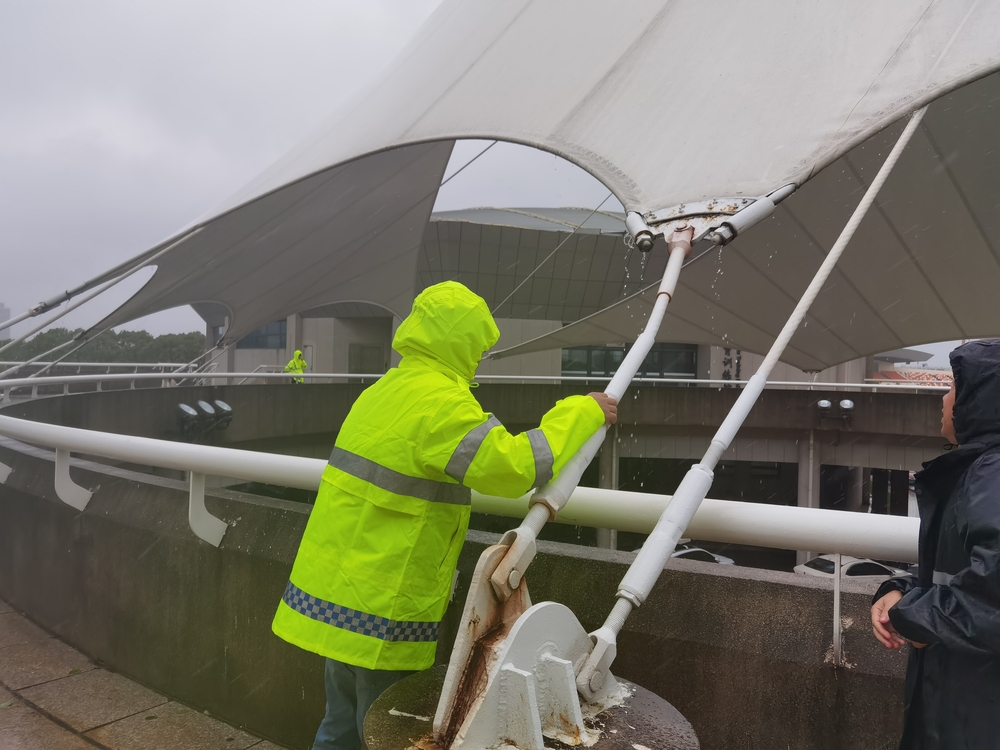 工作人员风雨中检查体育馆桅杆幕结构拉索紧固件