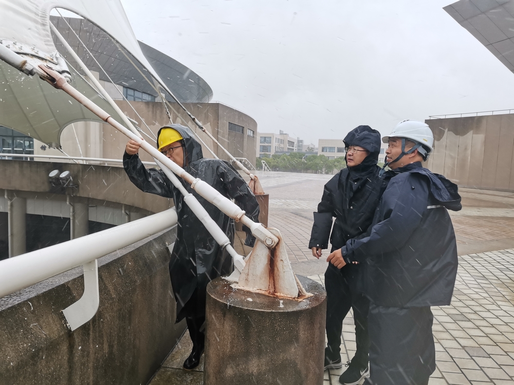 工作人员风雨中检查体育馆桅杆幕结构拉索紧固件